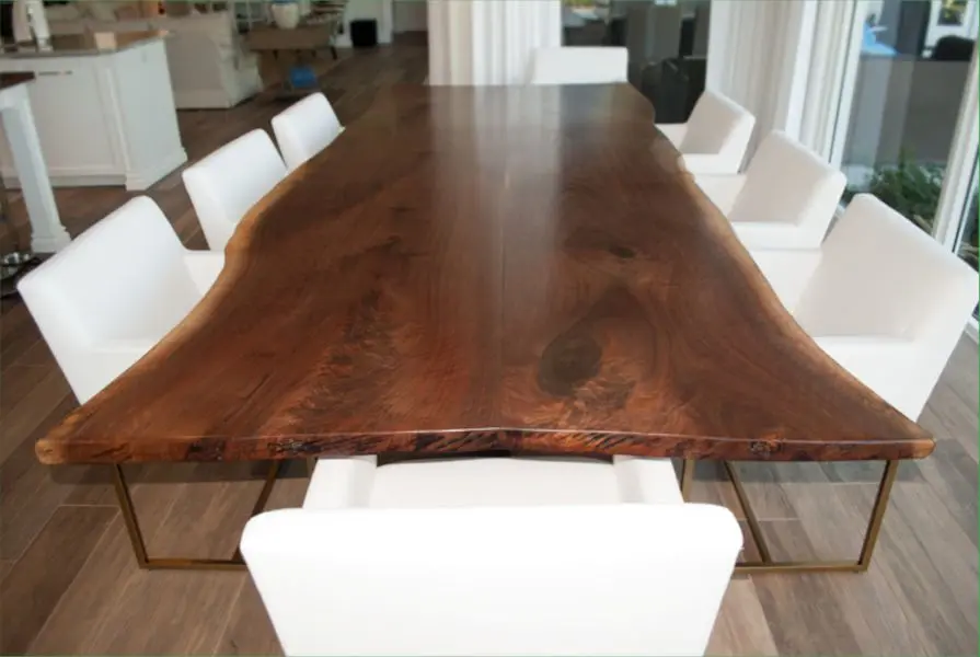 Custom black walnut dining table surrounded by white chairs
