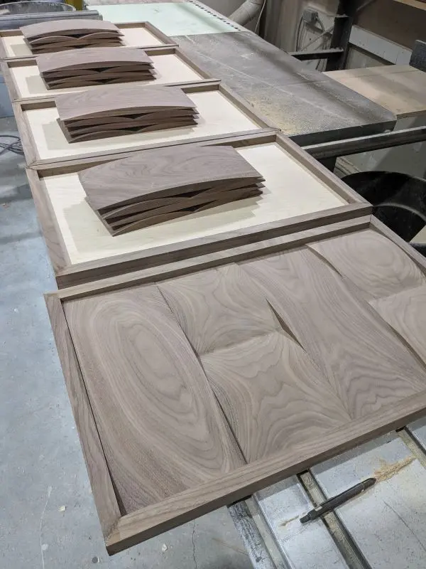 Assembled black walnut door with curved panels with additional doors ready for assembly